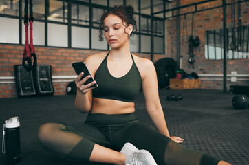 Woman, fitness and phone at gym for a workout, training and body wellness with a mobile app. Young sports female with smartphone for progress, performance and communication for a healthy lifestyle