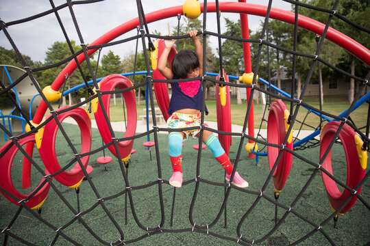 Girl in colorful knee socks climbing in park