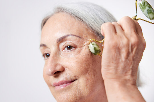 Female pensioner doing jade roller massage