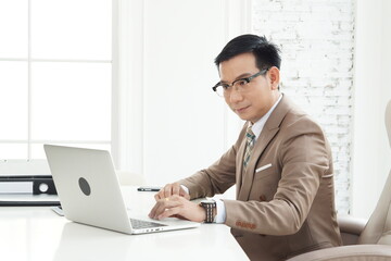 Asian handsome senior successful businessman using computer laptop to researching and working. sit in the private office 