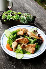 Typical Bavarian salad of turkey, vegetables and herbs on a wooden background.