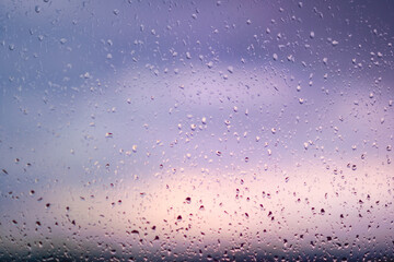 Natural water drops on a window agains a sunset sky.