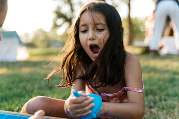 Amazed kid playing with sensory box items in park