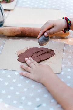 Anonymous kid playing with clay and seashell at table