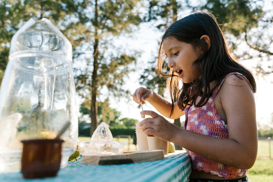 Cute child preparing juice at table during picnic in park