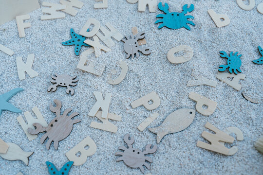 Different wooden toys scattered on sand in sensory box