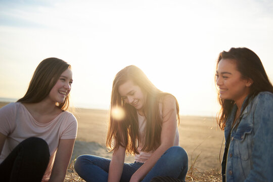 Happy female friends sitting on land against sky