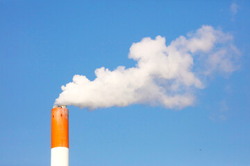 Smoke coming out of the chimney against the blue sky