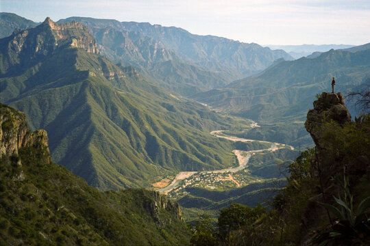 A young man looks down into Copper Canyon (Barrancas del Cobre) and the village of Urique, Chihuahua, Mexico.