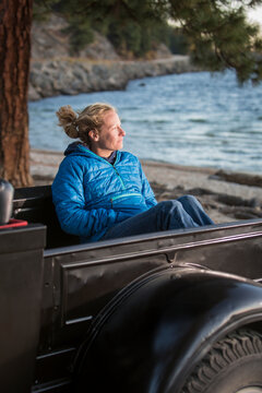 Woman sitting in renovated truck watching sunset, Payette Lake, McCall, Idaho, USA