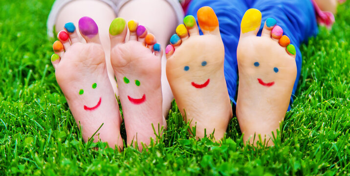 Children's feet with a pattern of paints smile on the green grass. Selective focus.