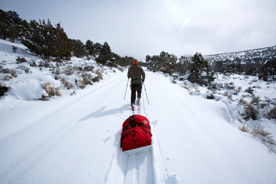 One man skiing and pulling a sled into a storm.