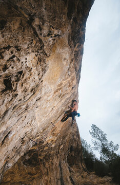 Shirtless climber sending a sport climbing route on spanish crag.
