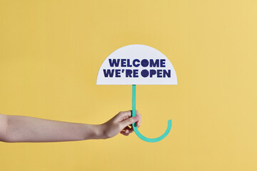 Welcome we're open, owner at the entrance to his store with a