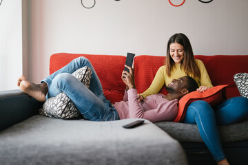 Merry diverse couple with tablet resting on couch