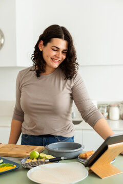Woman using tablet while cooking at home