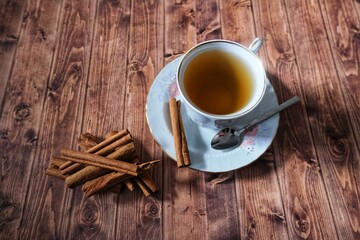 Cinnamon plant on wooden background and cinnamon tea in cup.