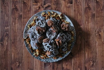 Dried date fruit in a plate. Background wooden floor.