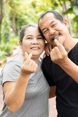 Senior couple, healthy old aging husband and wife showing asian style mini heart hand gesture