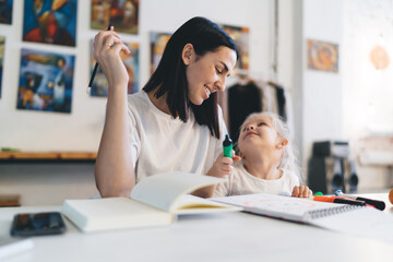 Fototapeta premium Cheerful woman and kid looking at each other while drawing