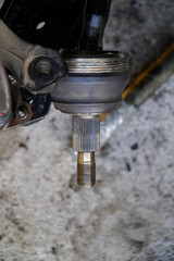 Left driveshaft of front axle with disc brake and ball joint, service center is replacing the driveshaft in the garage.