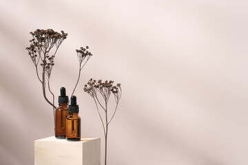 Face serum in glass dropper bottles on wooden podium with dry plants. Hyaluronic acid oil, collagen...