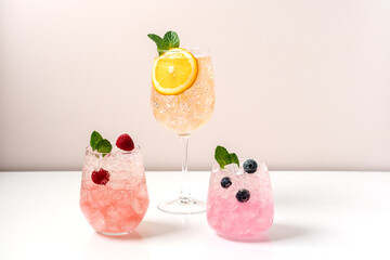 Set of drinks with ice in glasses. Raspberry, blueberry and orange cocktails. Refreshing tropical summer fruit lemonades