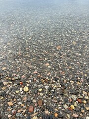 Pebbles on the bottom of the lake, transparent water, natural pebbles background
