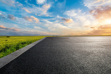 Asphalt road and green wheat fields natural scenery at sunrise