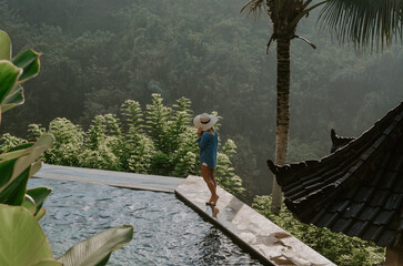 Young travelling girl swimming in the infinity pool in a luxurious home in Ubud, Bali, Indonesia. 