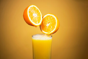 pouring juice into a glass from half an orange on an orange background