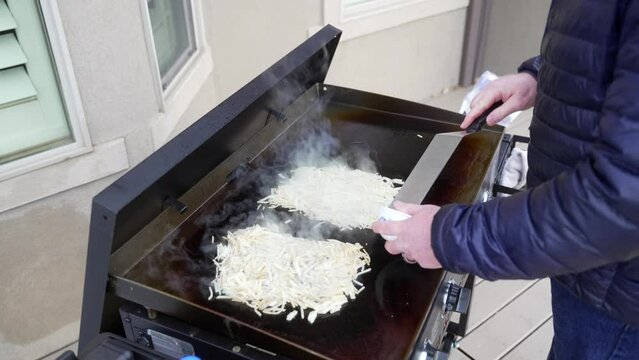 Sauteing peppers and onions on the flat top griddle to make hash brown omelets