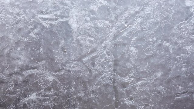 Ice and frost forms on glass window, during cold Winter. Background, pond, lake, freeze, close up, time lapse.
