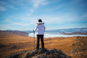 Fototapeta premium Traveller woman climbing and enjoy view of beautiful landscape natural snow mountain with sunset sky at Lake Baikal, Siberia, Russia. Recreation or Travel concept.