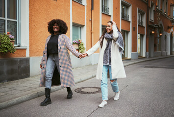 Fashion, holding hands and lesbian couple walking in street enjoying holiday, vacation and adventure on weekend. Love, lgbtq relationship and women together for happy lifestyle, freedom and relaxing - Powered by Adobe