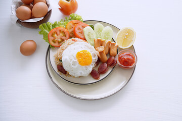 Fried rice and hot dogs, cooked fried egg, Chinese sausage and ketchup on a white background.