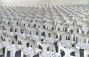Obraz premium Behind a large number of white plastic chairs were set up for watching the show.