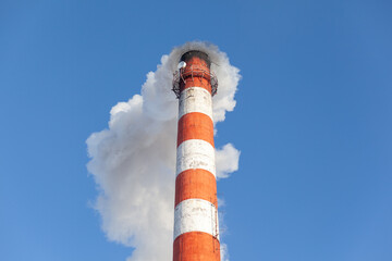 White thick smoke from the boiler room chimney. Smoke against the blue sky. Air pollution. Heating of the city. Industrial zone.