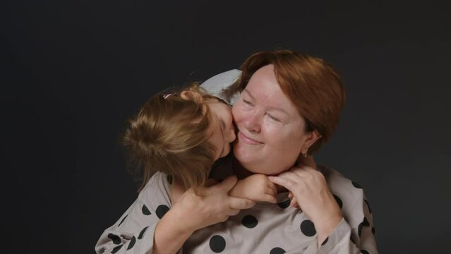 The concept of family love and love between generations. Beautiful granddaughter kisses and hugs her elderly grandmother