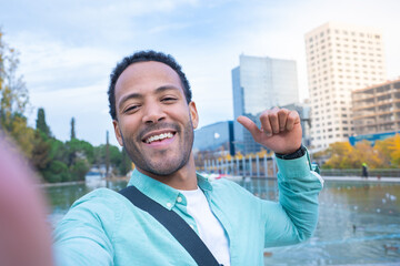 Attractive latin man taking a selfie looking at camera smiling. Happy student tourist traveling...