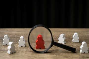 Concept of difference and leadership. White wooden puppets arranged in a circle, but one of them is...