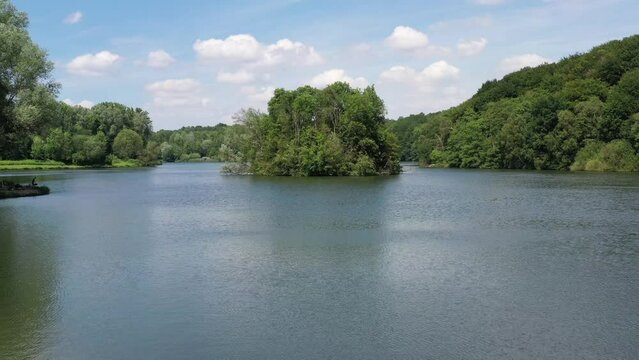 Low point of view of lake rising over island of trees in the middle of water
