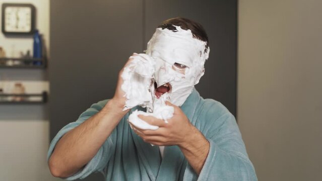 Portrait of a man with foam on his face and hands scaring into the camera