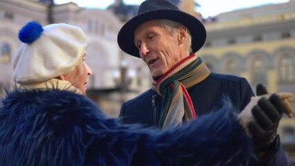 Positive senior man talking dancing with woman on city street enjoying leisure. Portrait of handsome Caucasian husband dating with wife outdoors on sunny spring autumn day