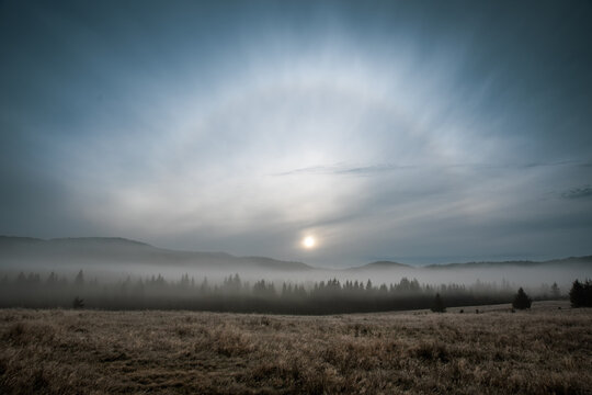 A sundog over the foggy forest in Carpathian Mountains at sunrise in autumn day. 