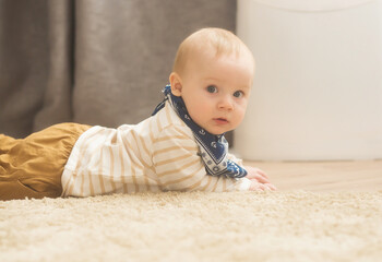 A baby at the age of 8 months learns to crawl at home. Cute little boy crawling on the floor.
