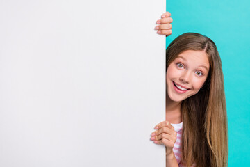Portrait of cheerful funky person peeking behind empty space proposition blank isolated on teal...