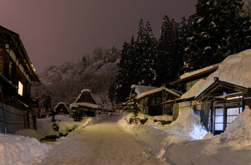 Narrow snow covered road through quiet village in mountains at night
