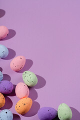 Bunch of colorful eggs with dots on purple background. Minimal Easter concept with copy space for text. 