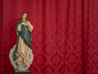 statue of the Virgin Mary on a red background. Catholic Church. Lord's mother